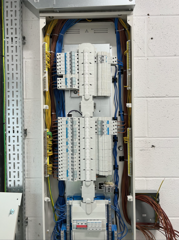 Engineers upgrading distribution equipment to meet electrical wiring regulations BS 7671 18th edition.