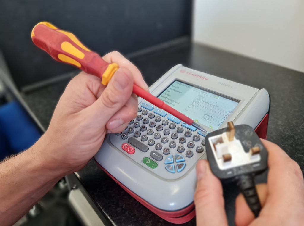 Technician performing Portable Appliance Testing (PAT) on a piece of equipment.