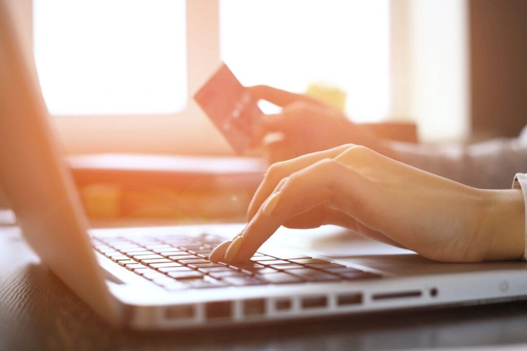 A laptop displaying a hand holding a card, symbolizing the IT buy-back service offered by MIT Commercial