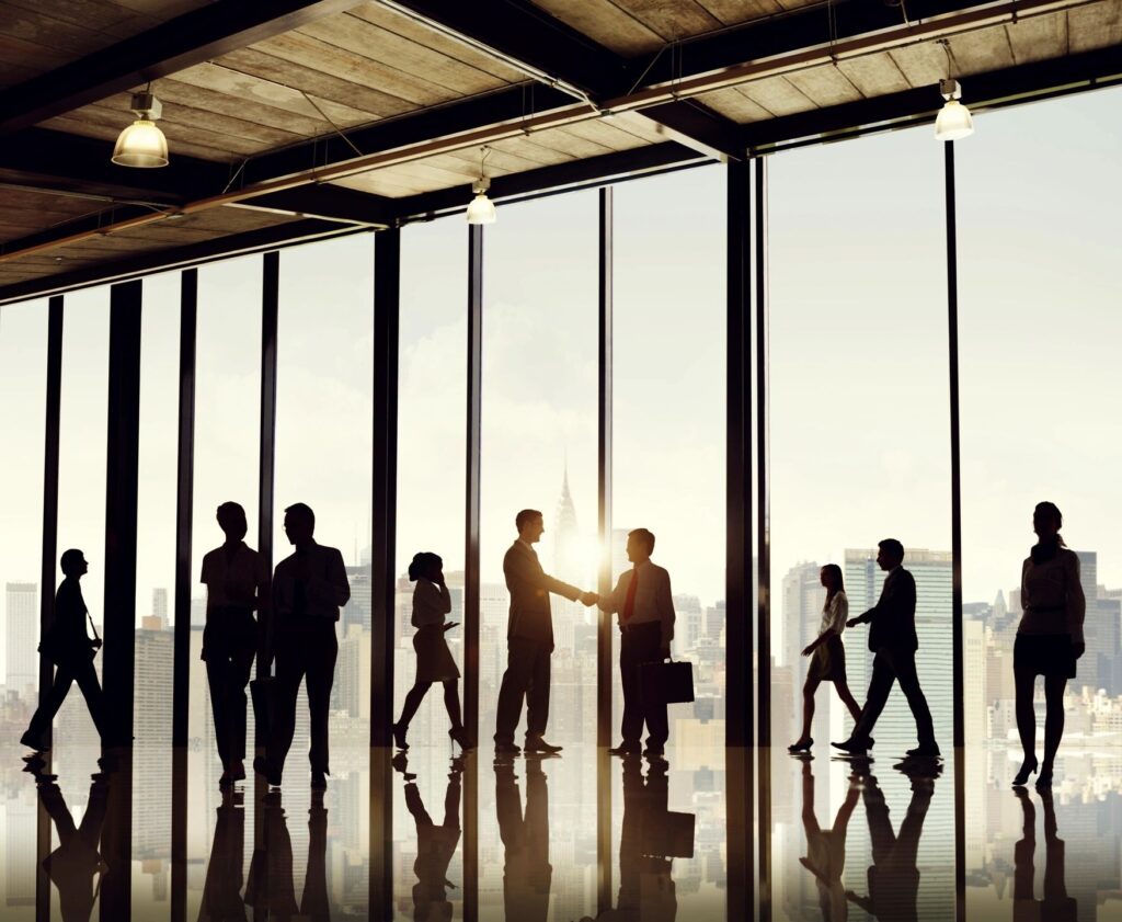 well lit office communal area, executives shaking hands & people walking about