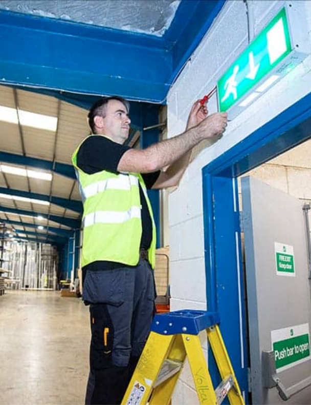 Technician Maintaining Illuminated Emergency Exit Sign